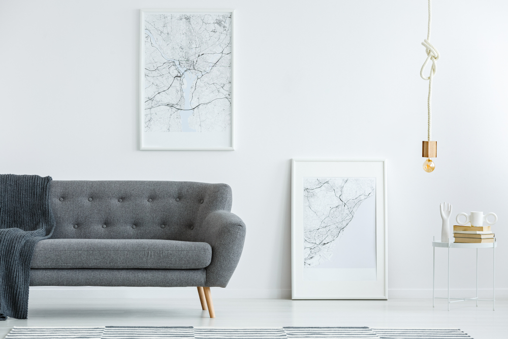 Example of minimalist decor with gray sofa, white tile flooring, focus on artwork and sparing accessories. From Graham's Fort Collins Flooring & Design.