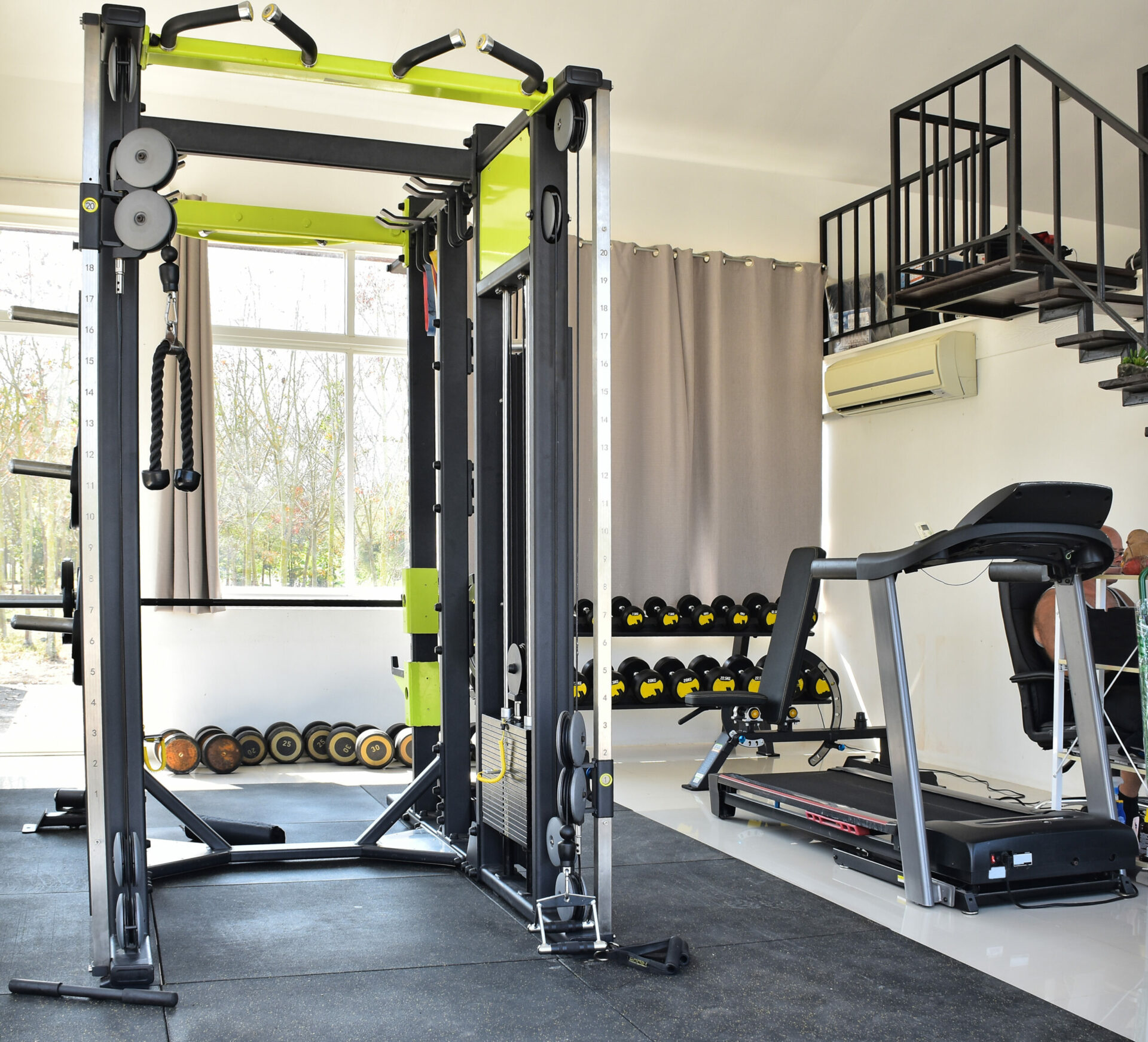 Squat bar, dumbbells and treadmill in home gym.